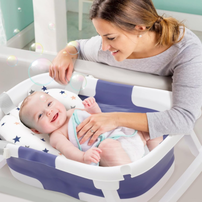 bébé souriant allongé sur son coussin moelleux dans baignoire bébé pliable