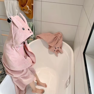 petite fille assise bord baignoire enveloppée cape bain bebe rose pâle capuche lapin