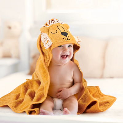 enfant souriant assis porte cape de bain bebe orange capuche lion franges.