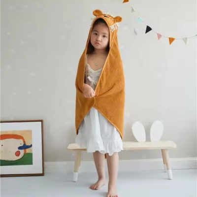petite fille debout porte cape bain bebe orange design capuche lion frange