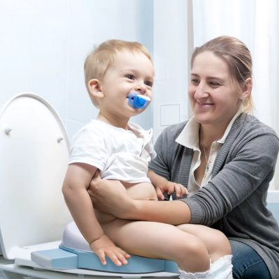 petit-garçon-souriant-assis-sur-pot-bebe-toilette-réducteur-avec-maman-heureuse-qui-tient-bébé