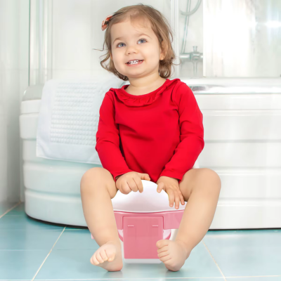 petite fille souriante assise sur pot bebe toilette rose dans toilette
