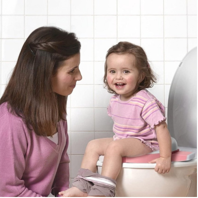 maman-regarde-petite-fille-souriante-assise-sur-réducteur-pot-bebe-toilette